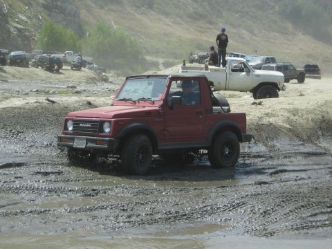 1987 Suzuki Samurai - Off-roading event with a 1987 Suzuki Samurai navigating a muddy track, other vehicles present.