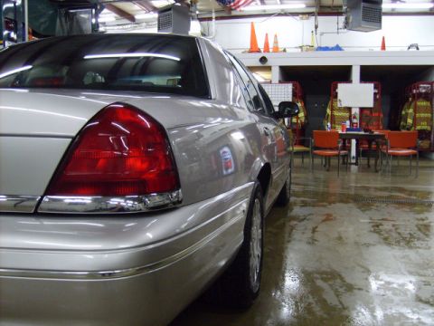 2004 Ford Crown Victoria - Rear quarter view of a silver sedan parked indoors, with fire station equipment visible in the background.