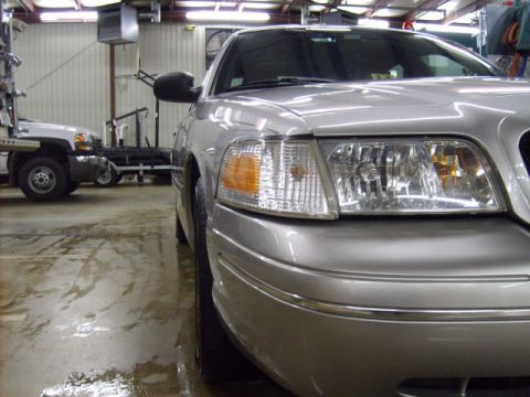 2004 Ford Crown Victoria - Front corner of a silver 2004 Ford Crown Victoria parked in a garage with another vehicle.