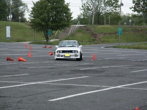 2001 Mercury Grand Marquis - A white BMW E30 navigates a course marked by orange cones in a parking lot.