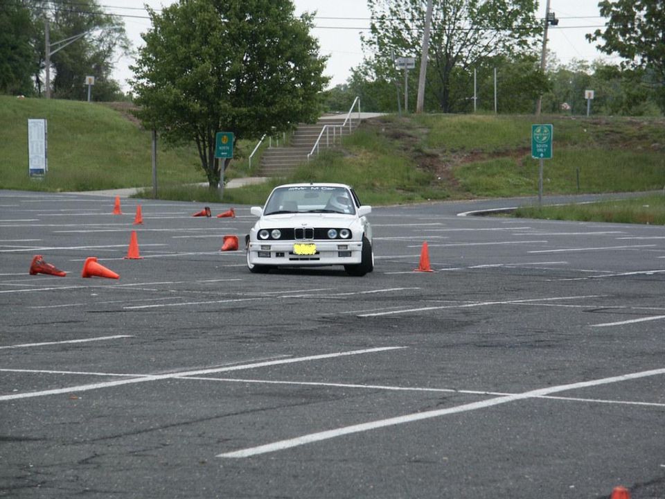 White BMW E30 with yellow license plate in a parking lot with orange cones