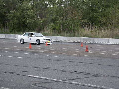 2001 Mercury Grand Marquis - A white BMW E30 M3 navigates an autocross course, indicated by the orange cones and racing number 11.