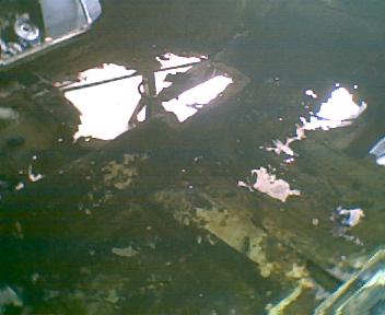 1973 Ford Ranchero - The undercarriage of a vehicle shows significant rust and damage, with holes revealing the sky above. The Supermotors.net logo is present i…