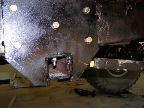 1993 Ford Bronco - This image shows a close-up view of a vehicle's frame undergoing modification, with a newly attached bracket and a tire visible in the back…