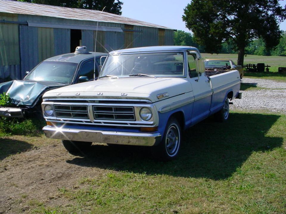 Two-tone blue and white Ford F-Series pickup truck parked next to a damaged green car