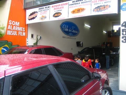 1995 Ford Taurus - A red car is in the foreground, with a black car and children visible behind it in a garage setting.