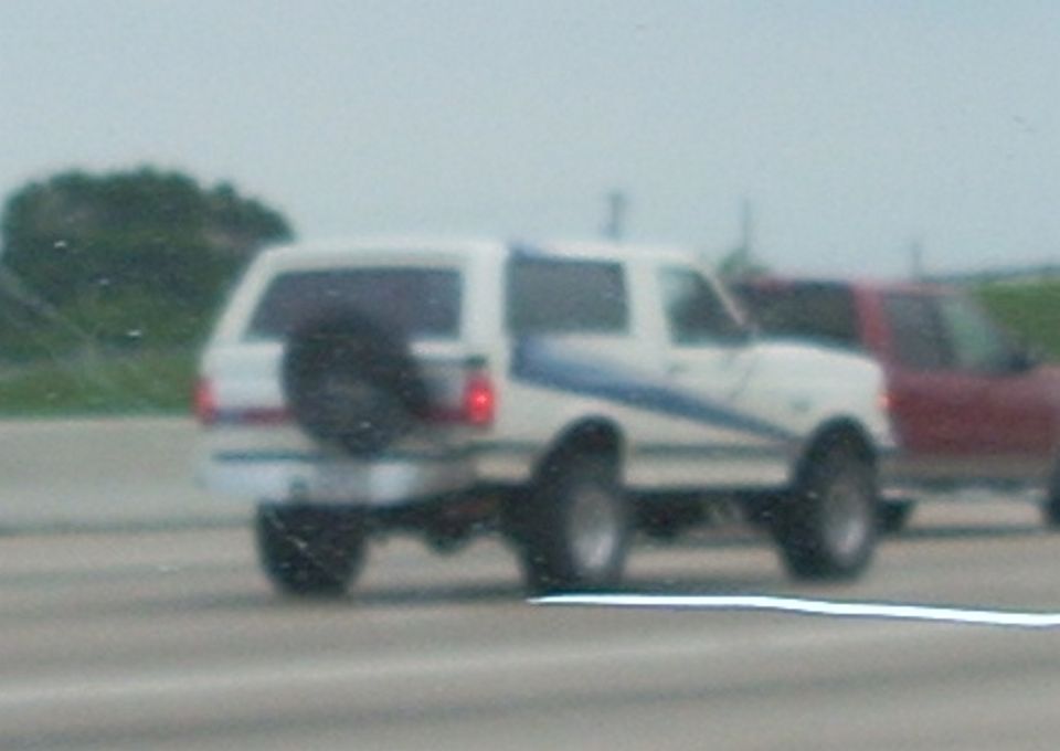 White 1992 Ford Bronco with blue stripe and rear spare tire