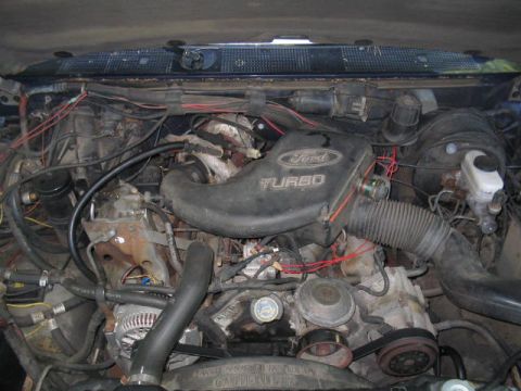 1979 Ford Bronco - Engine bay view of a Ford diesel/turbo engine with a black plastic intake cover reading 'Ford TURBO', showing the alternator, ribbed access…