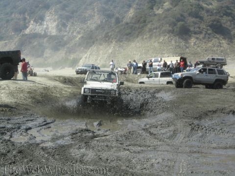 1987 Suzuki Samurai - Off-roading event with multiple vehicles navigating a muddy terrain.