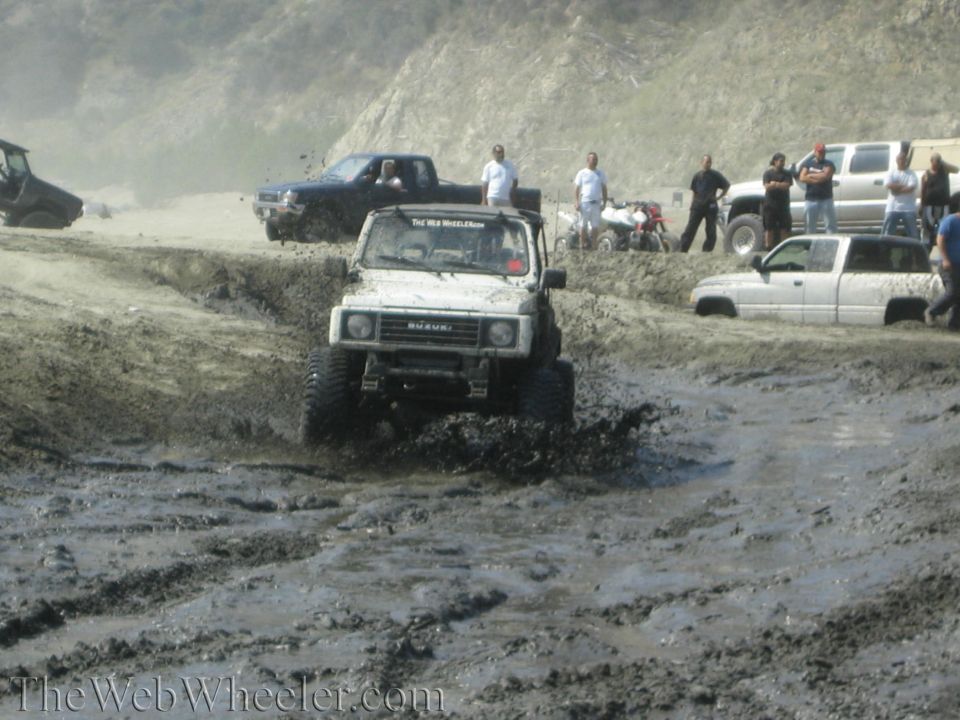 White 1987 Suzuki Samurai splashing through mud