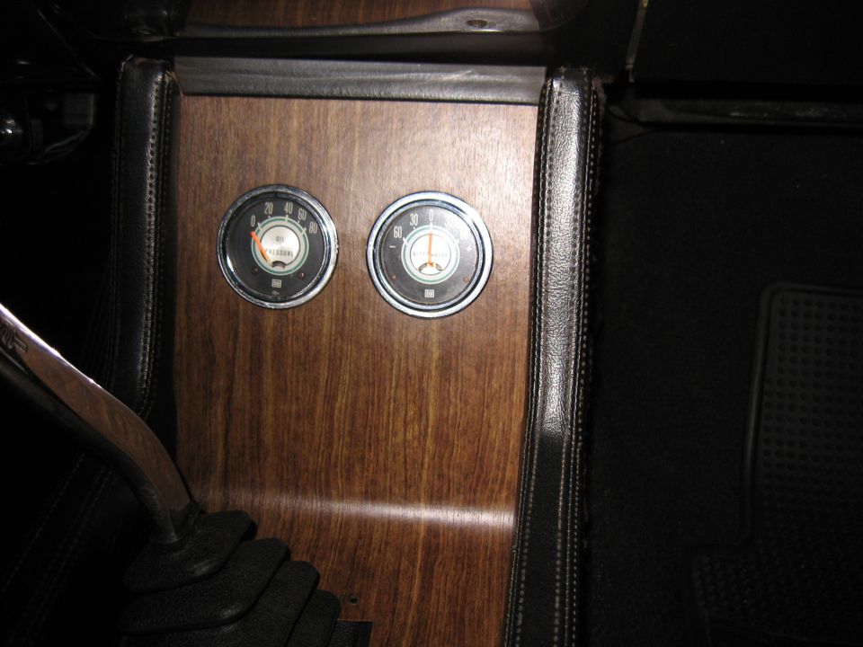 Woodgrain console with oil pressure and ammeter gauges beside a wood shifter
