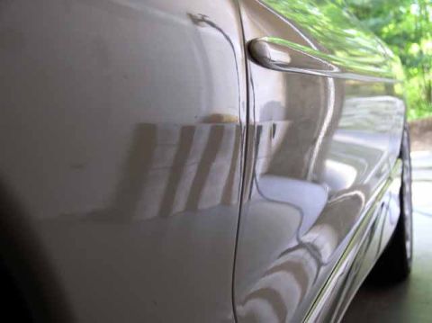 1996 Ford Probe - Close-up view of the side panel and door handle of a light-colored vehicle.