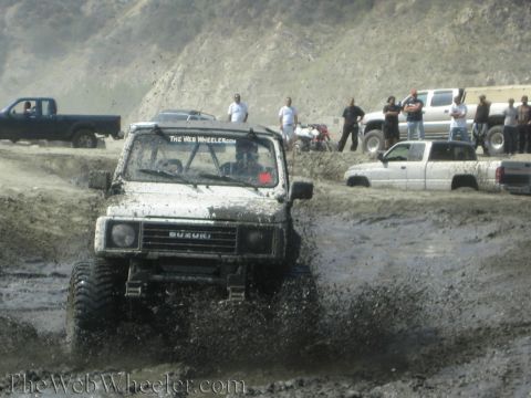 1987 Suzuki Samurai - Suzuki Samurai navigating a muddy off-road course with spectators and other vehicles present.