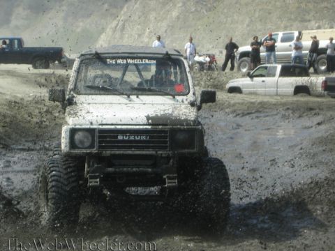 1987 Suzuki Samurai - Suzuki Samurai navigating a muddy off-road course with other vehicles present.