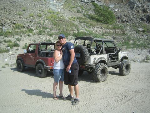 1987 Suzuki Samurai - Couple with two Suzuki Samurai off-road vehicles on a sandy terrain.
