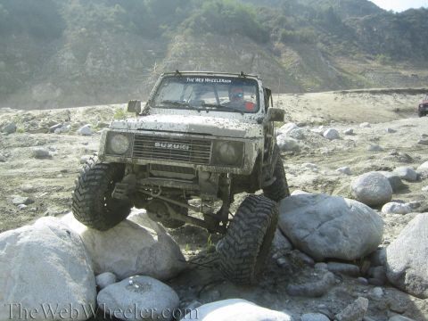 1987 Suzuki Samurai - A Suzuki Samurai navigates a rocky obstacle course on a sunny day.