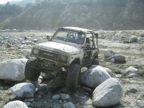 1987 Suzuki Samurai - Suzuki Samurai tackling rough terrain, climbing over large boulders.
