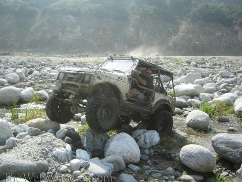 1987 Suzuki Samurai - Suzuki Samurai navigates a rocky terrain, kicking up dust.