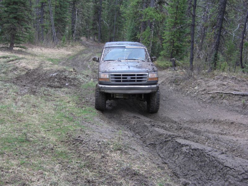 1995 Ford Bronco driving through mud on a forest trail