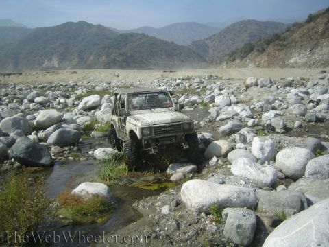 1987 Suzuki Samurai - Suzuki Samurai tackles a challenging rocky terrain in a dry riverbed.