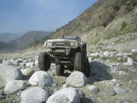 1987 Suzuki Samurai - A modified 1987 Suzuki Samurai navigates a rocky terrain with steep hills in the background.