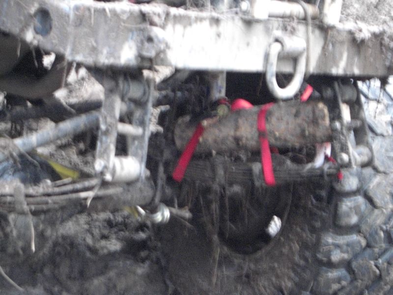 Mud-covered rear axle with red tow straps and leaf springs