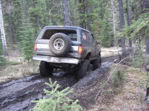 1995 Ford Bronco - This 1995 Ford Bronco navigates a challenging muddy path through a wooded area.