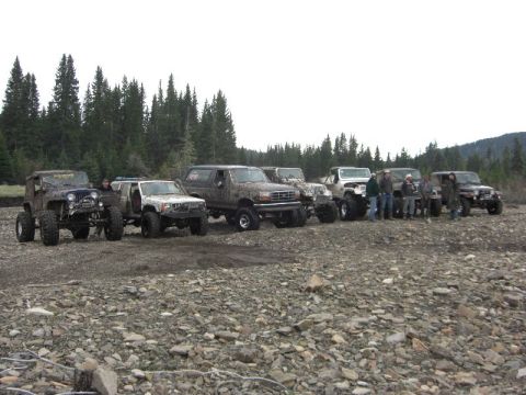 1995 Ford Bronco - A group of off-road enthusiasts and their customized vehicles gathered in a natural, rocky terrain.