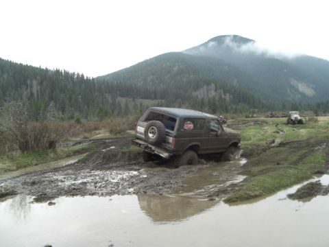 1995 Ford Bronco - Off-roading Bronco navigating a muddy trail with a second vehicle visible in the distance.