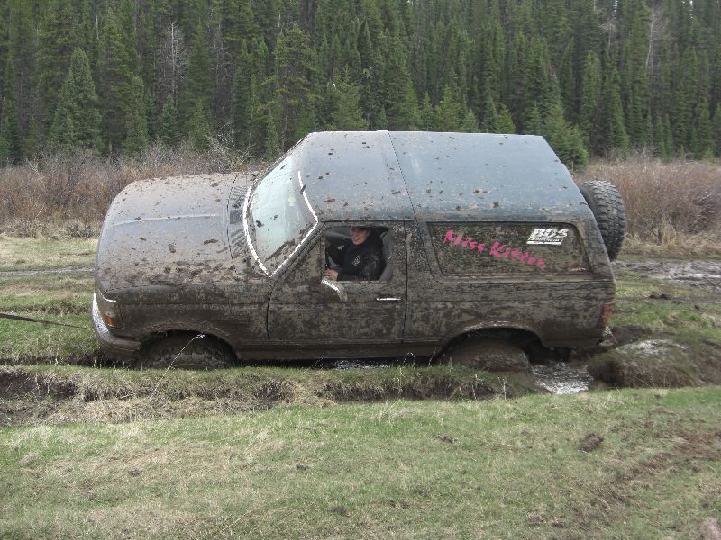 1995 Ford Bronco stuck in mud with pink lettering on the rear window