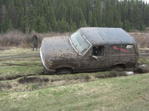 1995 Ford Bronco - This SUV is deeply stuck in the mud, with its tires submerged in the mire.
