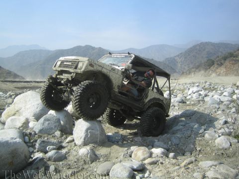 1987 Suzuki Samurai - A driver navigates a Suzuki Samurai over a rocky obstacle course in a mountainous, arid landscape.