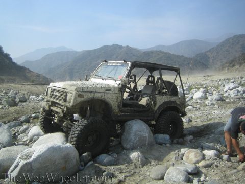 1987 Suzuki Samurai - This 1987 Suzuki Samurai navigates a challenging rocky terrain, covered in mud from its off-road adventure.