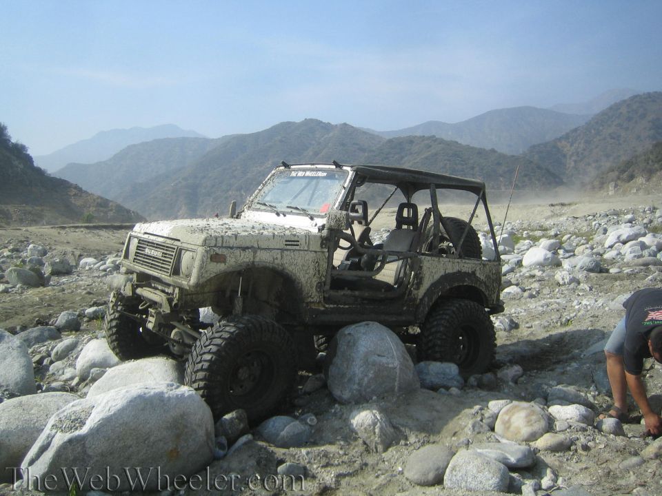 White 1987 Suzuki Samurai off-roading on a rocky, dusty trail