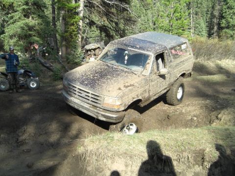 1995 Ford Bronco - Mud-covered 1995 Ford Bronco is stuck in a ditch off-road.