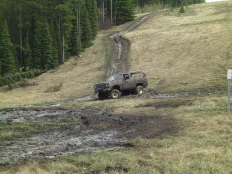 1995 Ford Bronco - This SUV is navigating a challenging muddy terrain on a hill.