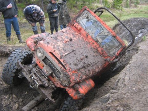1995 Ford Bronco - This Toyota Land Cruiser is deep in the mud, with onlookers observing its predicament.