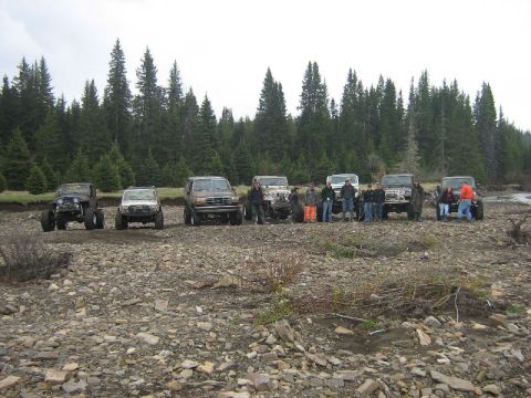 1995 Ford Bronco - A group of off-road enthusiasts pose with their vehicles in a natural, rocky landscape.