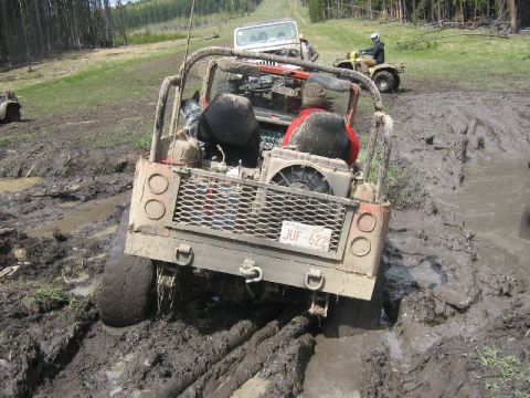 1995 Ford Bronco - Multiple vehicles navigate a muddy off-road course, with one vehicle deeply mired in the mud.