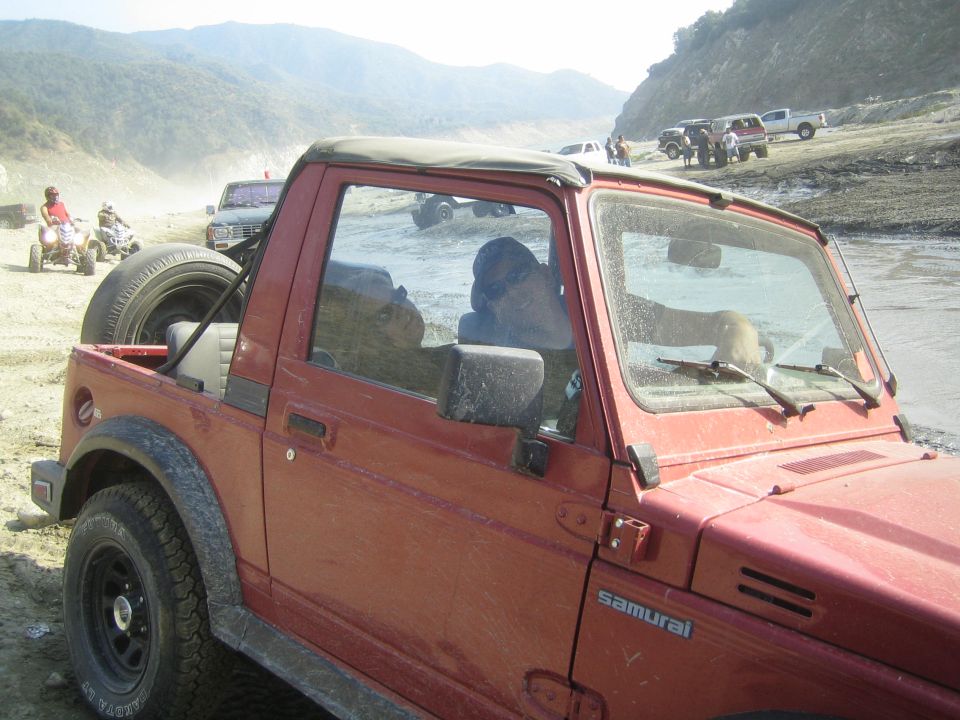 1987 Suzuki Samurai in a dirt landscape with other vehicles in the background