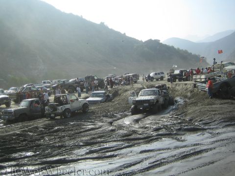1987 Suzuki Samurai - A large group of off-road vehicles are stuck in thick mud during an event, with spectators watching from the sidelines.