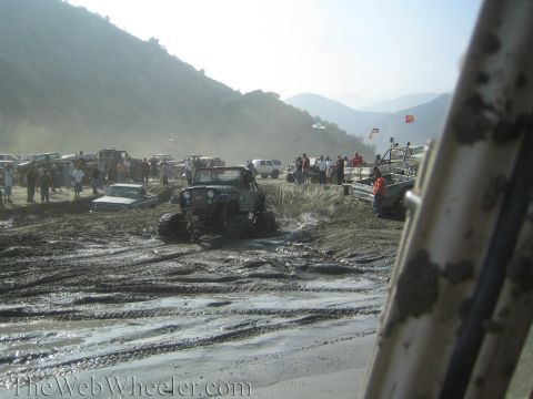 1987 Suzuki Samurai - A group of off-road vehicles navigate a muddy terrain, with spectators observing the action.