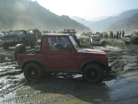 1987 Suzuki Samurai - Off-road event with multiple vehicles navigating a muddy terrain.