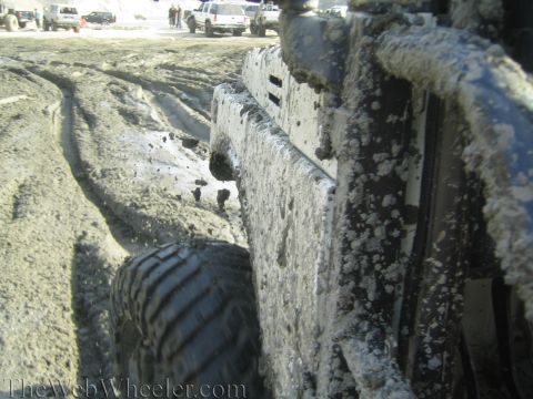 1987 Suzuki Samurai - A vehicle navigates a muddy track, with other vehicles visible in the background.