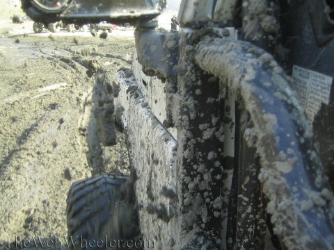 1987 Suzuki Samurai - This vehicle is covered in mud, driving through a muddy track with other vehicles visible.