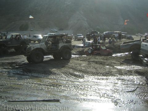 1987 Suzuki Samurai - A group of off-road vehicles navigate a muddy terrain, with some appearing to be stuck.