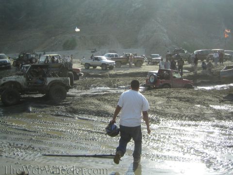 1987 Suzuki Samurai - Off-road vehicles navigate a muddy terrain, with several vehicles partially submerged.