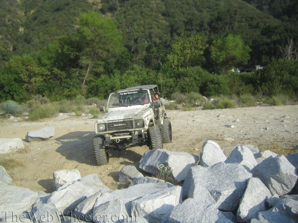White 1987 Suzuki Samurai navigating rocky terrain