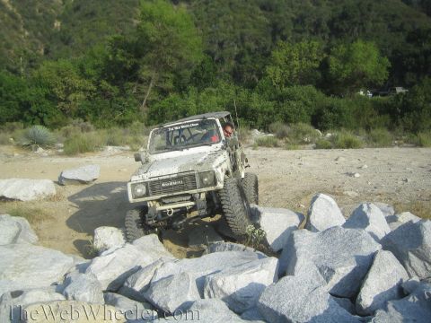 1987 Suzuki Samurai - Suzuki Samurai tackling a challenging rocky terrain off-road.