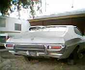 1973 Ford Ranchero - The rear of a 1972 Ford Gran Torino Sport is visible, parked in a dirt lot with a trailer nearby.